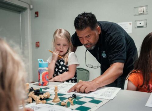 Chess instructor teaches student in chess class.