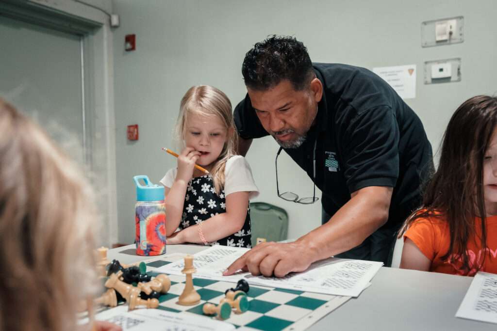 Chess instructor teaches student in chess class.